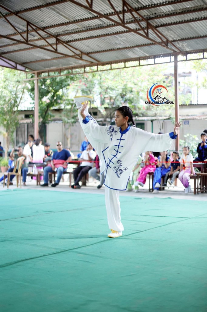 Junior athlete performs balance posture on the taolu mat