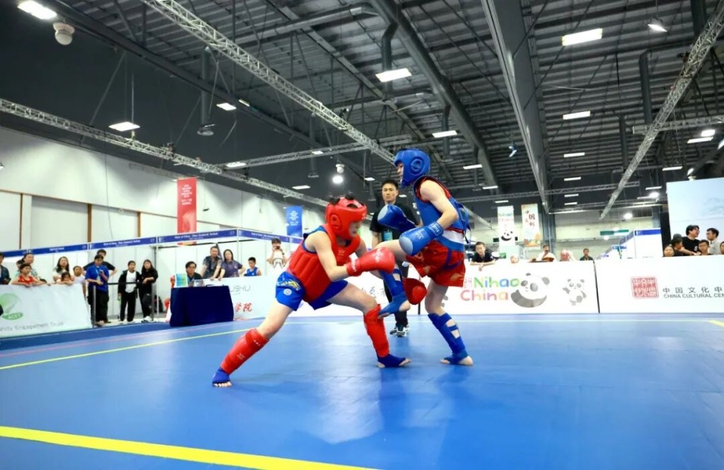 Sanda athletes in protective gear during competition.